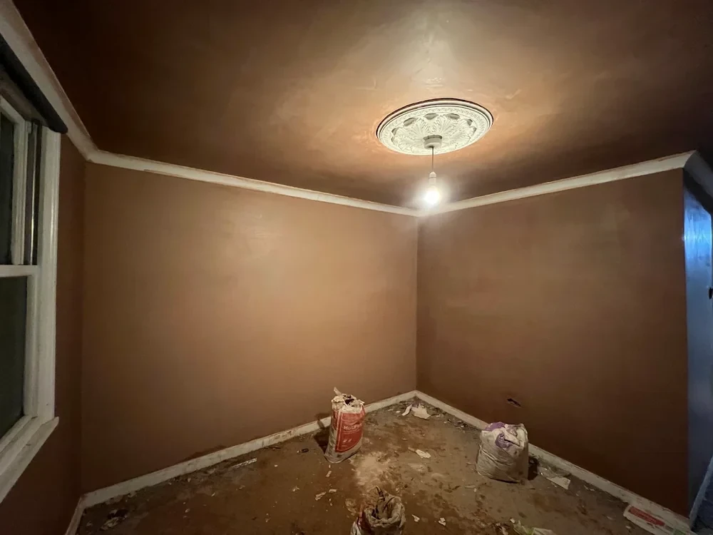 Newly plastered room during refurbishment with coving and ceiling rose in place